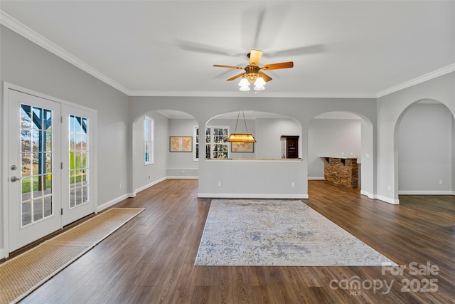 unfurnished living room featuring ceiling fan, baseboards, dark wood finished floors, and crown molding