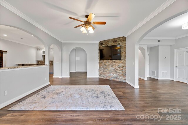 unfurnished living room featuring visible vents, arched walkways, a ceiling fan, and wood finished floors