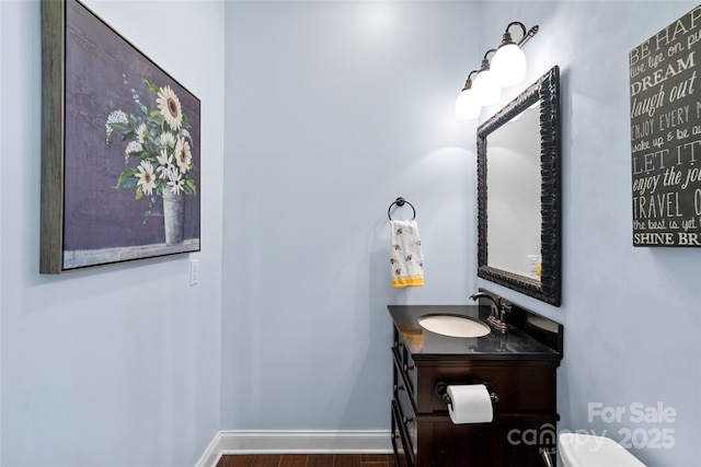 half bath featuring toilet, baseboards, wood finished floors, and vanity