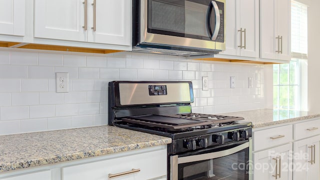 kitchen with white cabinets, backsplash, stainless steel appliances, and light stone counters