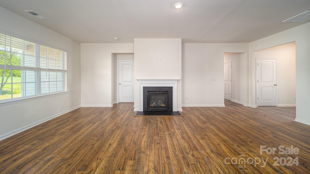 unfurnished living room featuring a healthy amount of sunlight and dark hardwood / wood-style floors