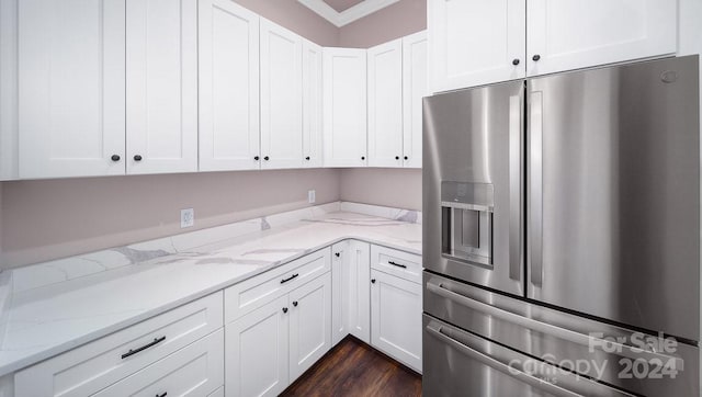 kitchen with stainless steel fridge, white cabinets, light stone counters, and ornamental molding