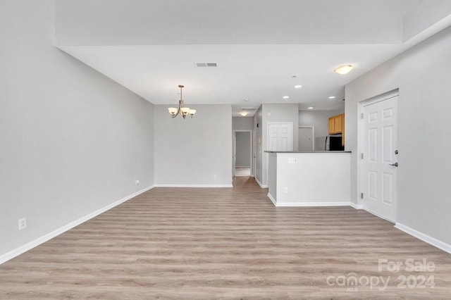 unfurnished living room featuring light hardwood / wood-style floors and a chandelier