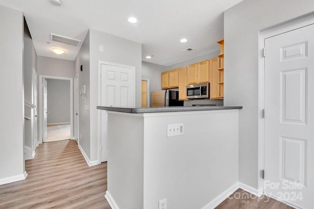 kitchen featuring kitchen peninsula, light brown cabinetry, stainless steel appliances, and light hardwood / wood-style floors