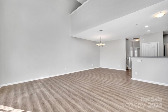 unfurnished living room with a chandelier and wood-type flooring