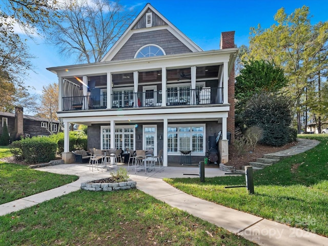 back of property featuring a sunroom, a yard, a balcony, and a patio