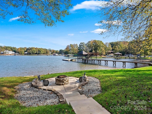 dock area with a fire pit, a water view, and a lawn