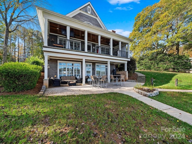 back of property featuring a yard, a patio area, an outdoor living space, and a balcony