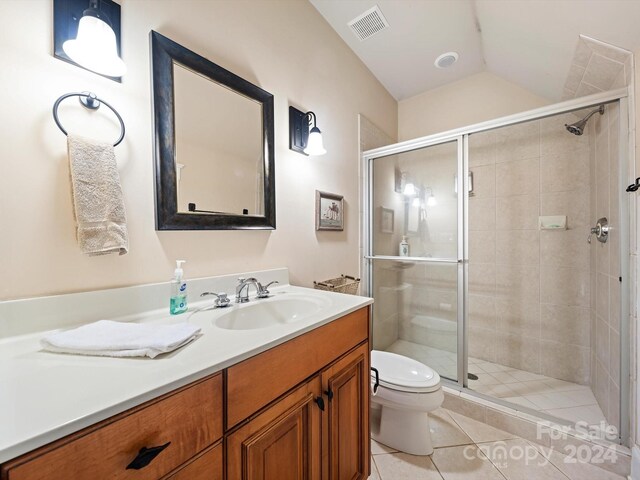 bathroom with vanity, tile patterned floors, vaulted ceiling, toilet, and walk in shower