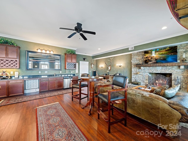 living room with dark hardwood / wood-style flooring, a stone fireplace, and crown molding