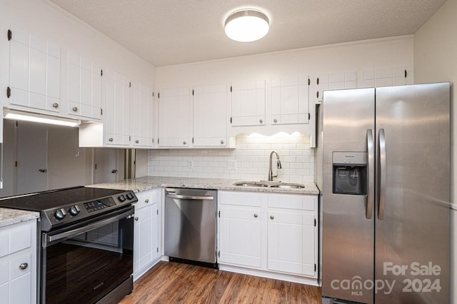 kitchen featuring light stone countertops, sink, dark hardwood / wood-style flooring, white cabinets, and appliances with stainless steel finishes