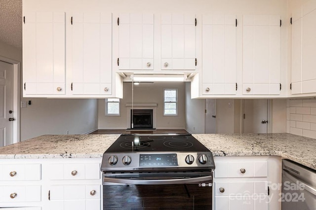 kitchen with appliances with stainless steel finishes, white cabinetry, and light stone counters