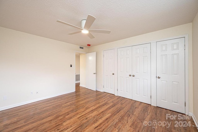 unfurnished bedroom featuring ceiling fan, a closet, wood-type flooring, and a textured ceiling