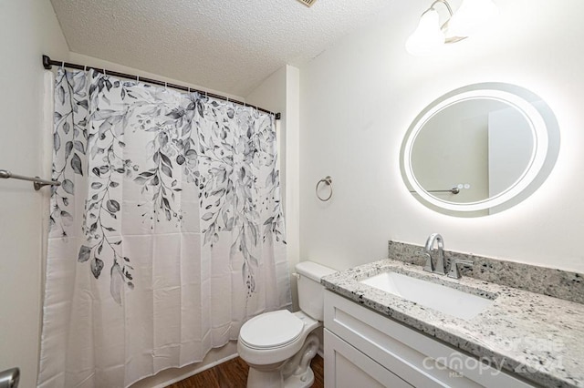 bathroom featuring vanity, hardwood / wood-style floors, a textured ceiling, and toilet