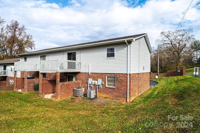 rear view of property with cooling unit and a yard