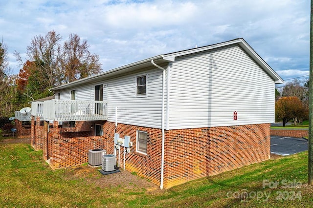 view of side of home with central air condition unit, a wooden deck, and a yard