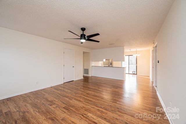 unfurnished living room featuring hardwood / wood-style floors, ceiling fan with notable chandelier, and a textured ceiling