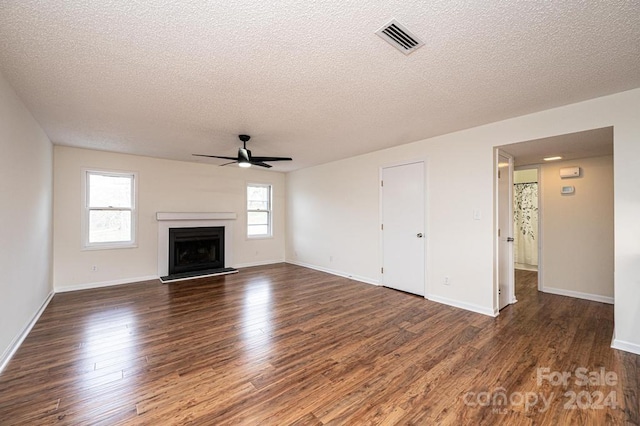 unfurnished living room featuring dark hardwood / wood-style floors, ceiling fan, a textured ceiling, and a wealth of natural light