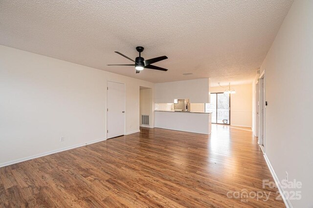 123 23rd St NW Unit E, Hickory, NC 28601 - unfurnished living room with wood finished floors, a textured ceiling, a ceiling fan, a chandelier, and baseboards