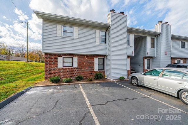 123 23rd St NW Unit E, Hickory, NC 28601 - view of front of home featuring uncovered parking, brick siding, a chimney, and a front lawn