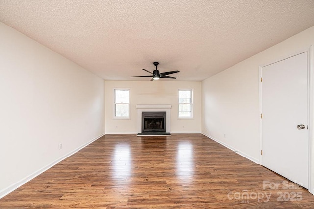 123 23rd St NW Unit E, Hickory, NC 28601 - unfurnished living room with a ceiling fan, wood finished floors, a textured ceiling, a fireplace with raised hearth, and baseboards