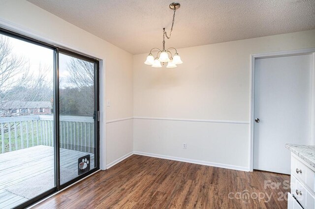 123 23rd St NW Unit E, Hickory, NC 28601 - unfurnished dining area featuring a chandelier, dark wood finished floors, a textured ceiling, and baseboards