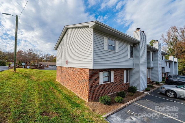123 23rd St NW Unit E, Hickory, NC 28601 - view of property exterior featuring uncovered parking, brick siding, a lawn, and a chimney