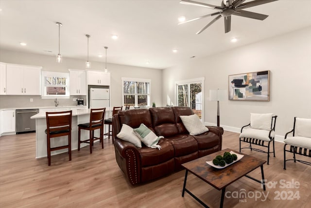 living room with ceiling fan, light hardwood / wood-style flooring, and sink