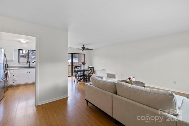 living room with ceiling fan, sink, and light hardwood / wood-style flooring