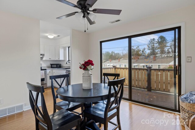 dining room with ceiling fan, sink, and light hardwood / wood-style flooring