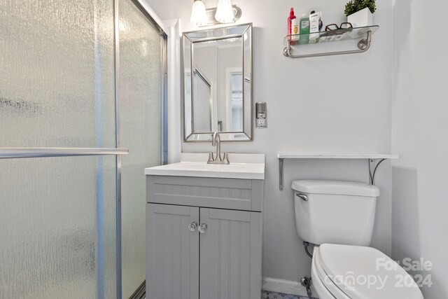 bathroom with vanity, toilet, and a shower with door