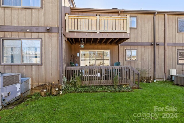 rear view of house featuring a lawn, central air condition unit, and a balcony