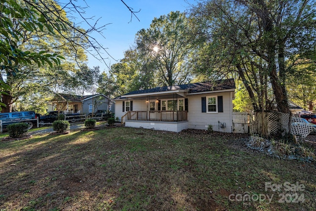 rear view of property with covered porch and a lawn