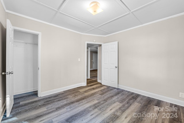 unfurnished bedroom featuring coffered ceiling, dark wood-type flooring, and a closet