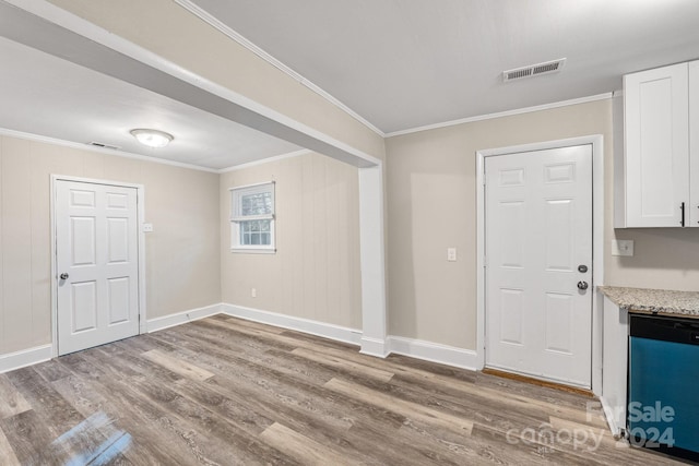 foyer with wooden walls, ornamental molding, and light wood-type flooring