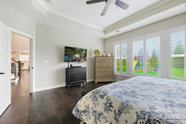 bedroom featuring a tray ceiling, crown molding, ceiling fan, and dark wood-type flooring