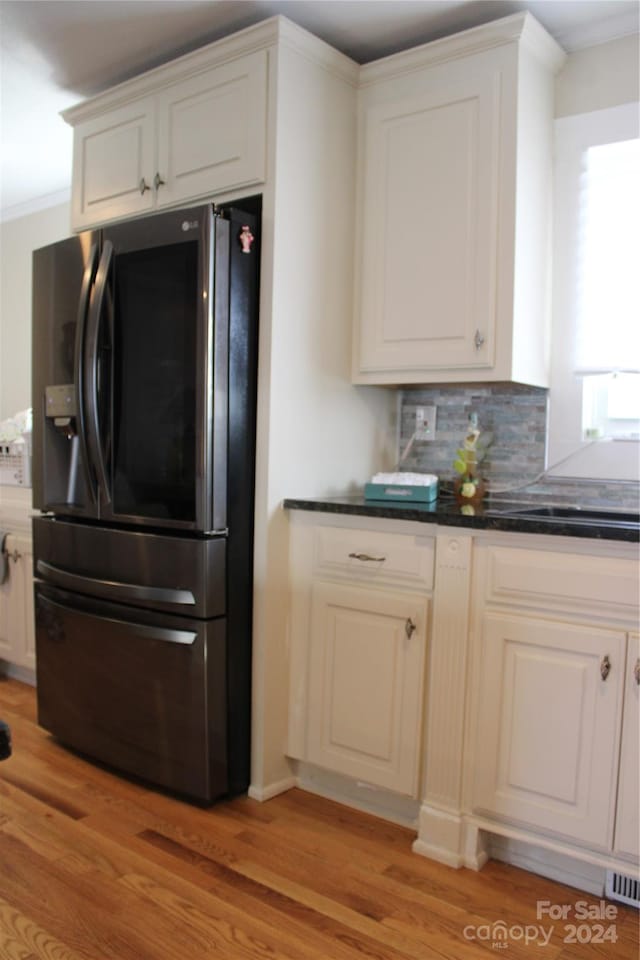 kitchen with refrigerator with ice dispenser, decorative backsplash, ornamental molding, and light hardwood / wood-style flooring