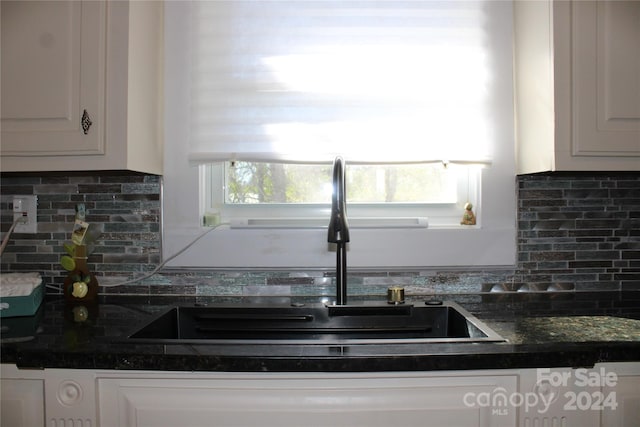 kitchen with backsplash, white cabinetry, and sink