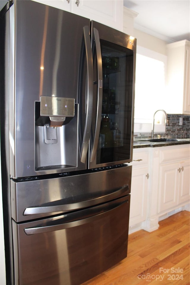 kitchen with sink, backsplash, stainless steel fridge, light hardwood / wood-style floors, and white cabinets