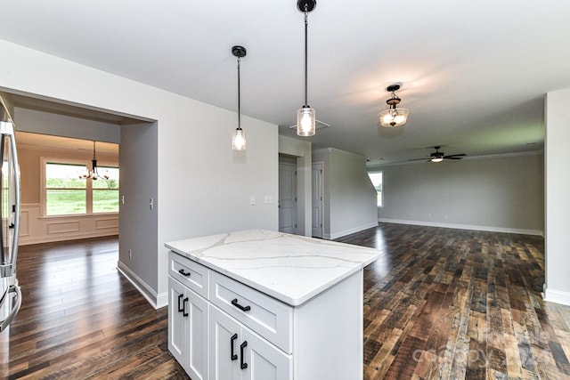 kitchen with light stone counters, ceiling fan with notable chandelier, dark wood-type flooring, white cabinetry, and hanging light fixtures