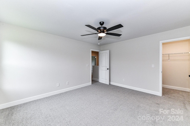 unfurnished bedroom featuring carpet flooring, a closet, a spacious closet, and ceiling fan