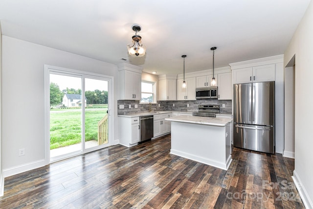 kitchen featuring white cabinets, appliances with stainless steel finishes, decorative light fixtures, and dark wood-type flooring