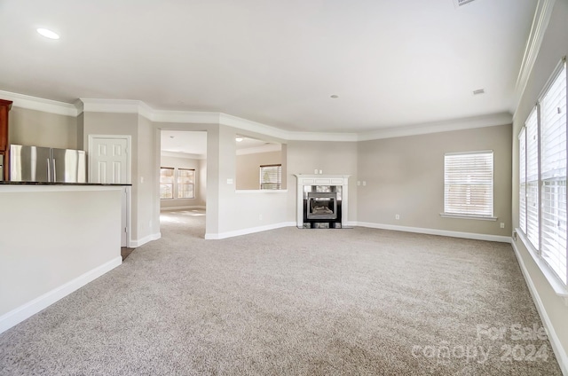 unfurnished living room featuring a wealth of natural light, light carpet, and ornamental molding