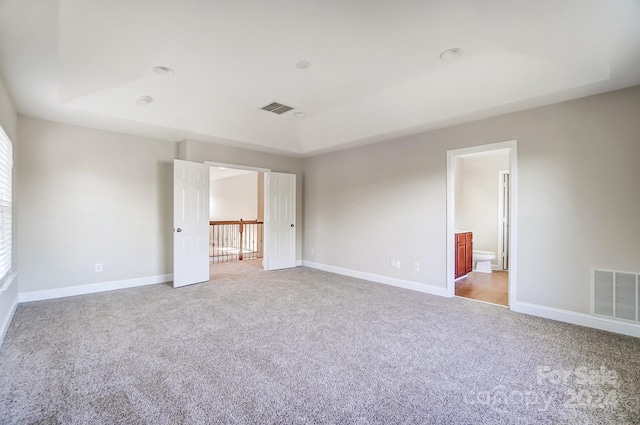 unfurnished bedroom with light carpet and connected bathroom