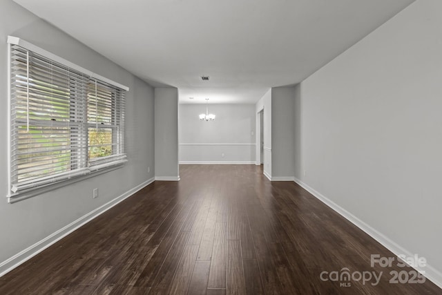 empty room featuring dark hardwood / wood-style floors and an inviting chandelier