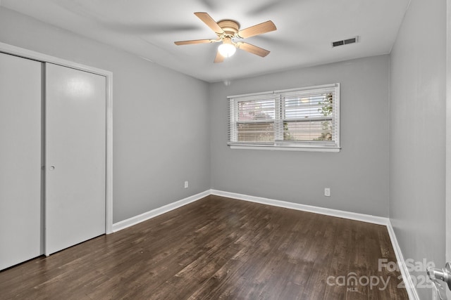 unfurnished bedroom with ceiling fan, a closet, and dark hardwood / wood-style flooring