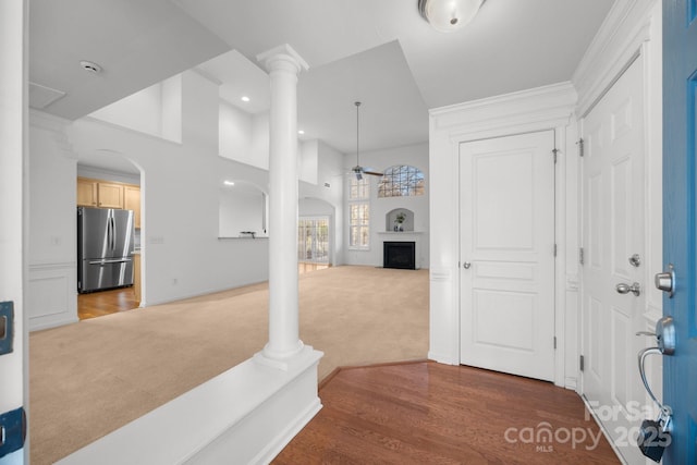 foyer entrance with dark colored carpet, ceiling fan, and decorative columns