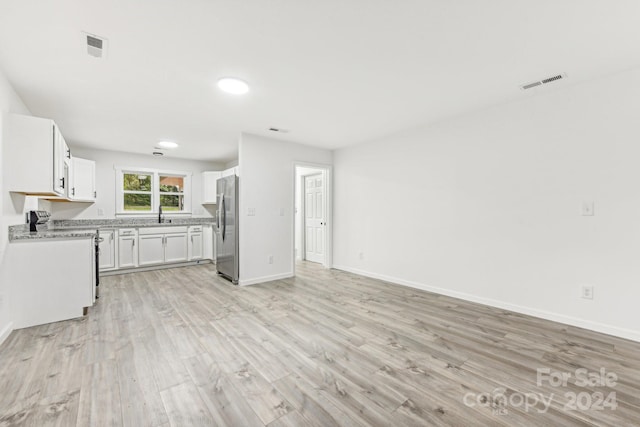 kitchen featuring stainless steel refrigerator, white cabinetry, light hardwood / wood-style flooring, and range