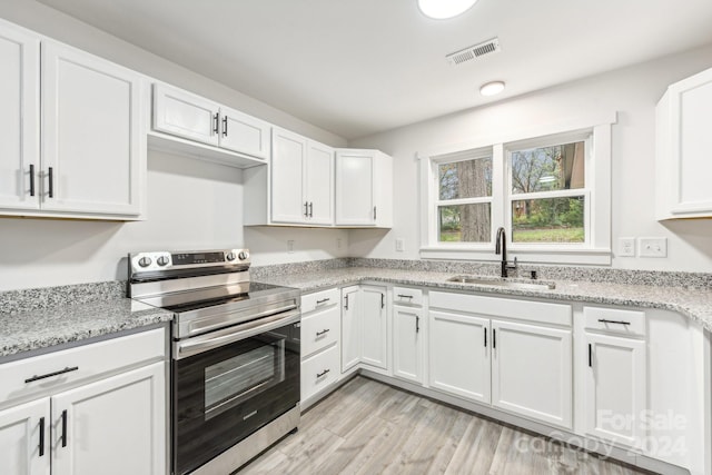 kitchen with electric stove, white cabinetry, sink, and light hardwood / wood-style flooring