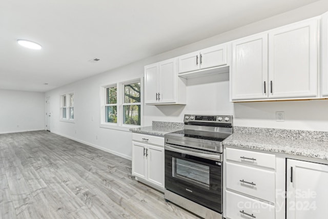 kitchen featuring stainless steel range with electric stovetop, white cabinets, light stone countertops, and light hardwood / wood-style flooring